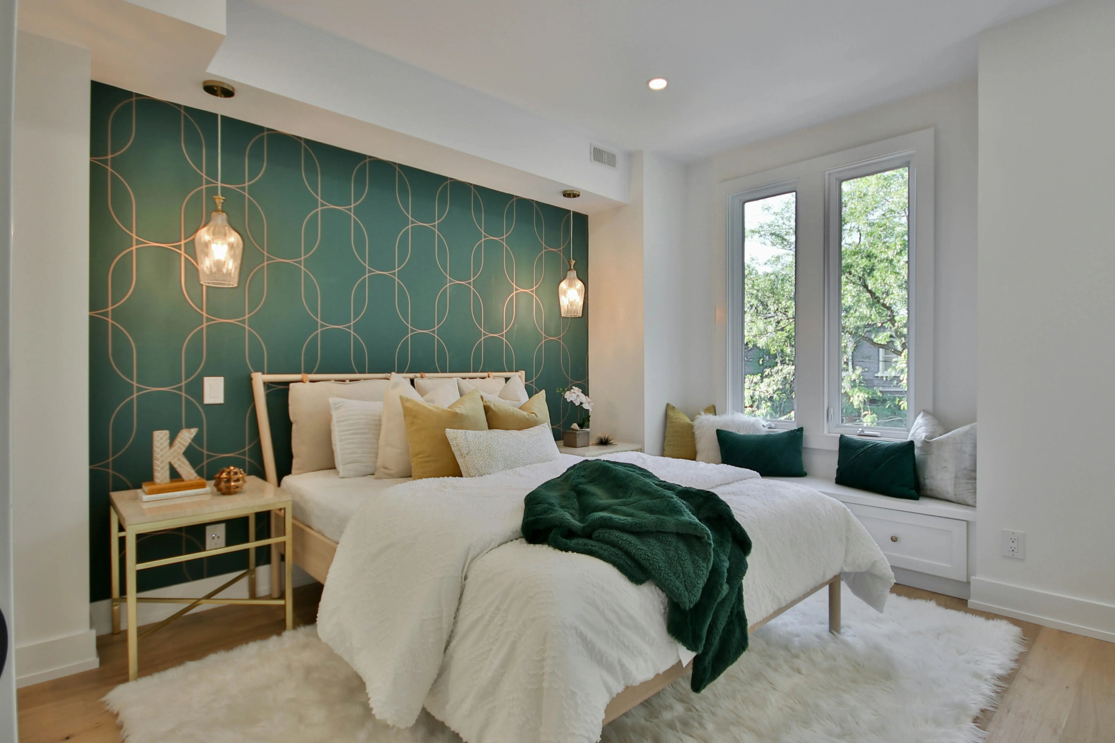 Stylish bedroom featuring soft cotton bedding, green throw blanket, and gold pendant lights for a cozy vibe.