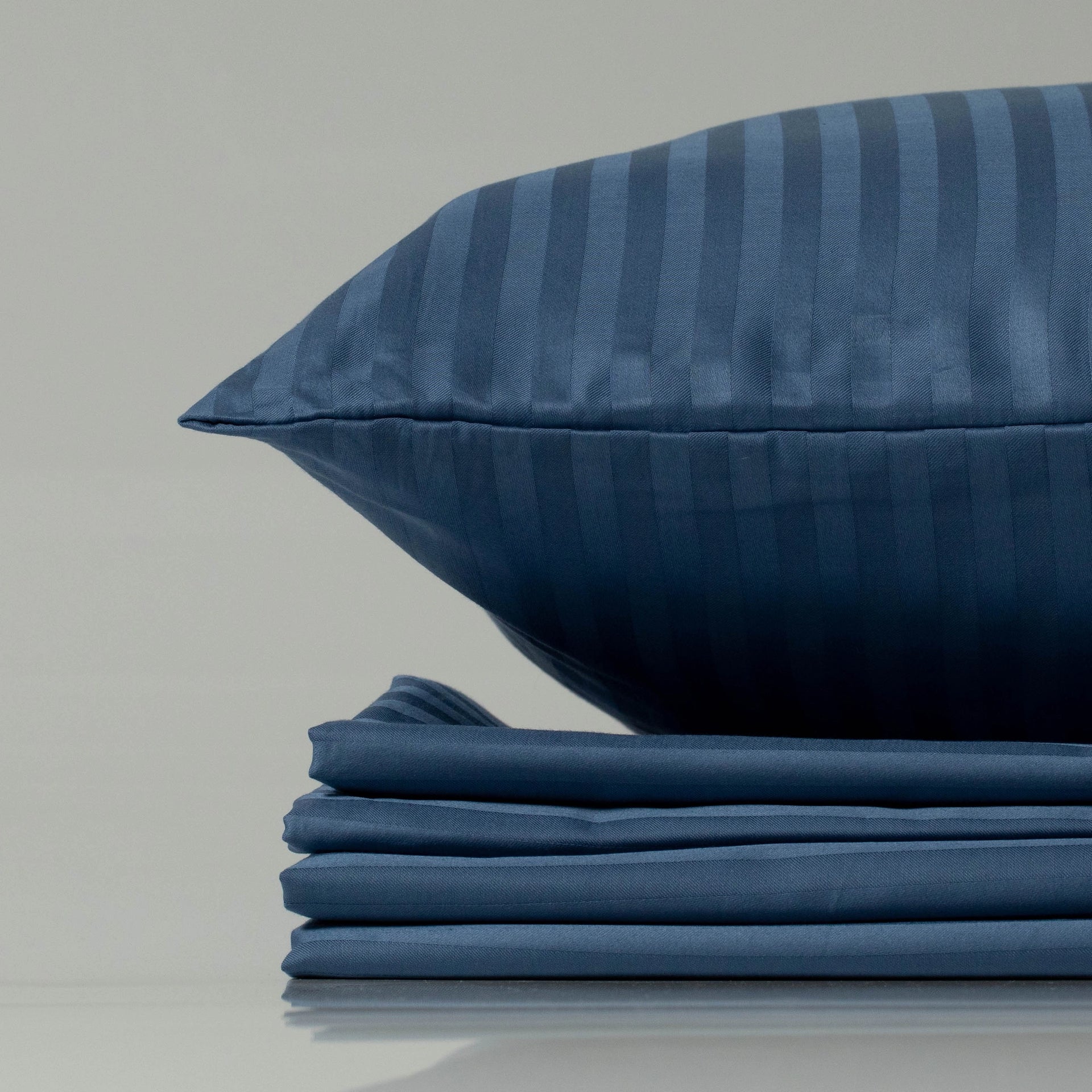 Navy blue striped sateen pillow and folded sheet set—eco-friendly, custom-crafted luxury from Supreme Rest