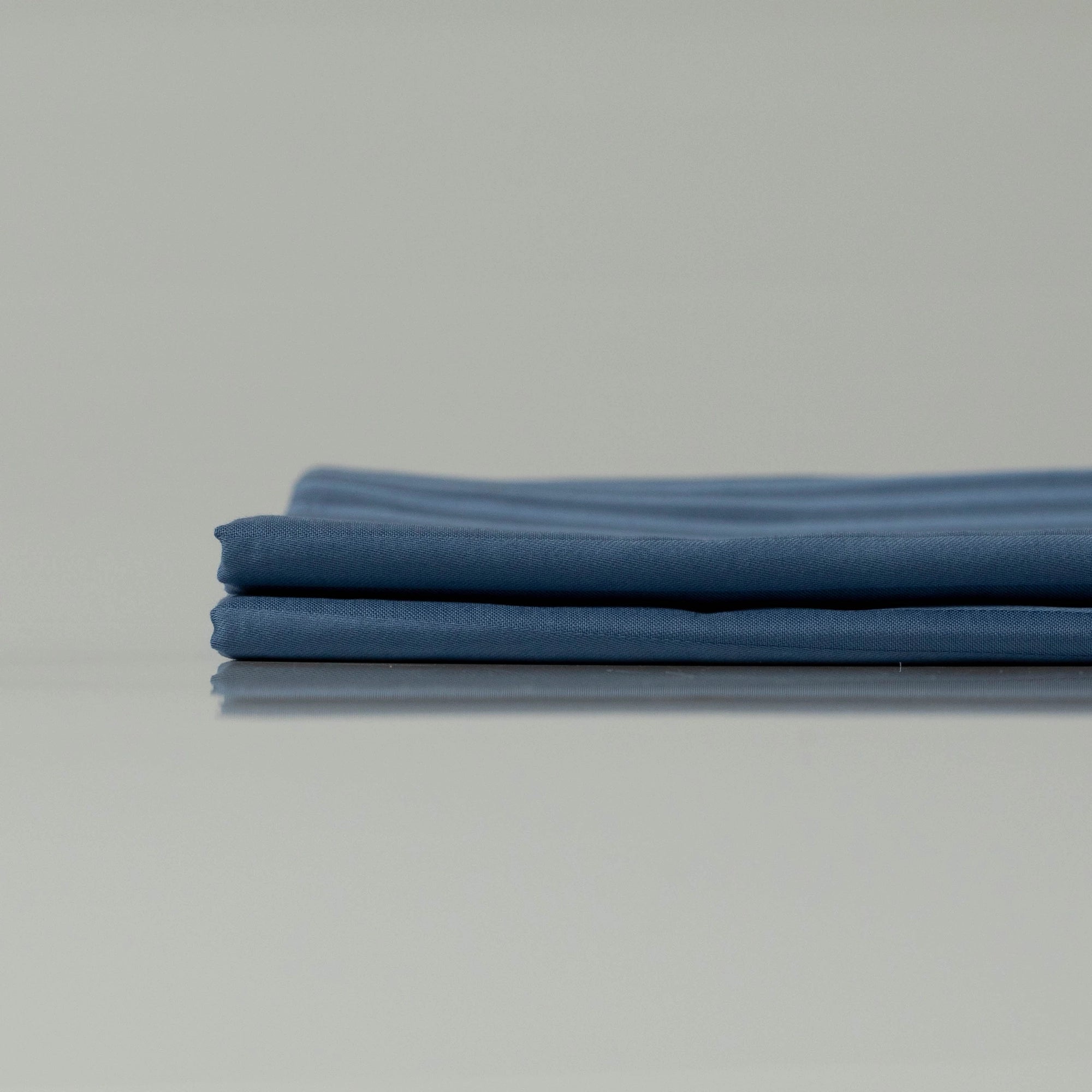 Minimalist display of neatly folded navy striped pillowcases, highlighting their refined stitching and smooth, breathable fabric
