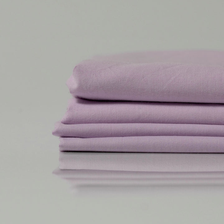 Neatly folded lilac ranforce sheets stacked on top of each other
