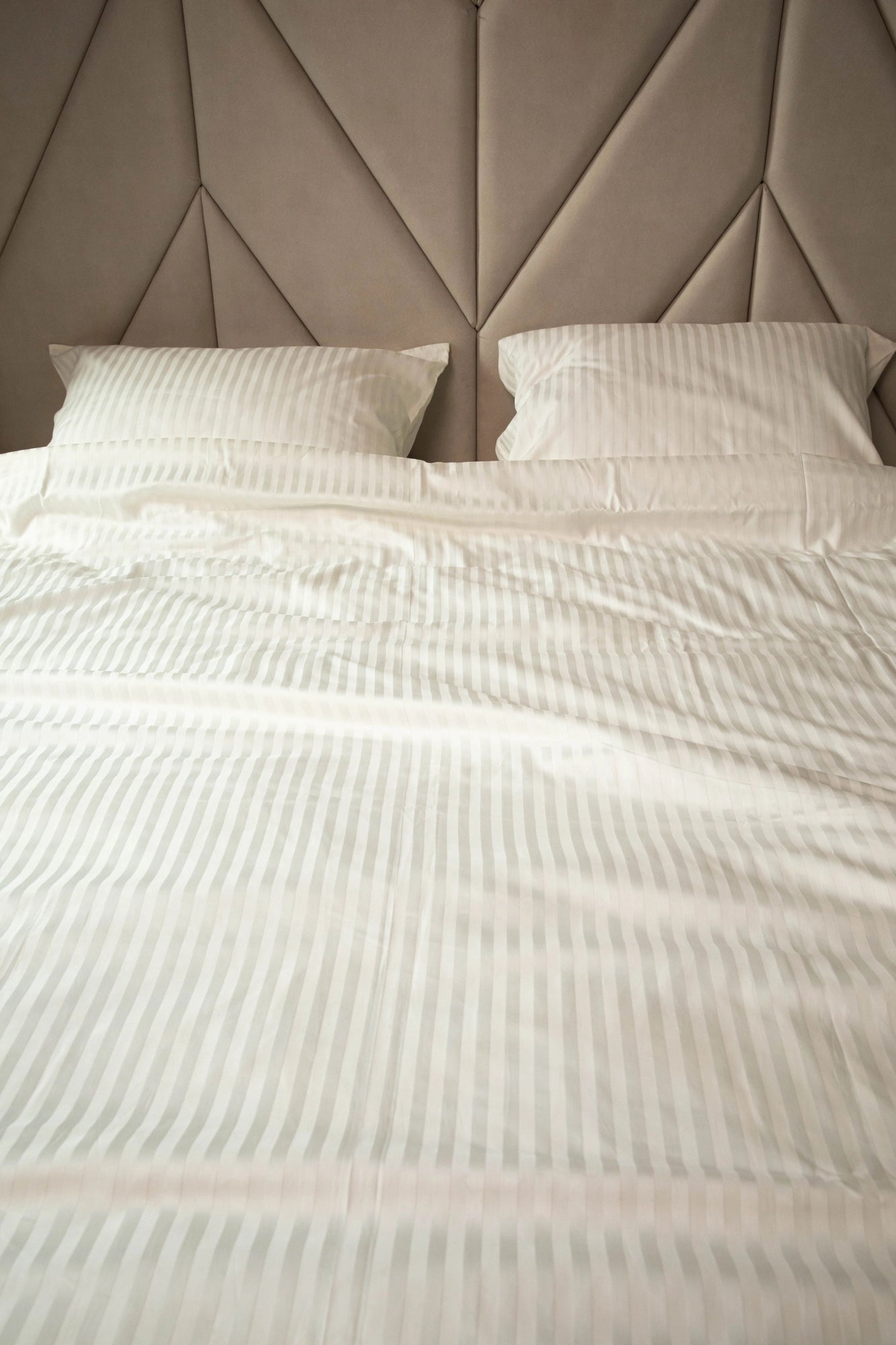 Luxurious Ivory Dune bedding set with silky pillowcases and a duvet cover on a modern bed.