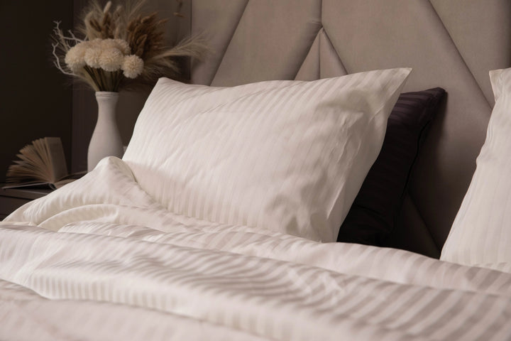 Luxurious Ivory Dune bedding set with silky pillowcases and a duvet cover on a modern bed.