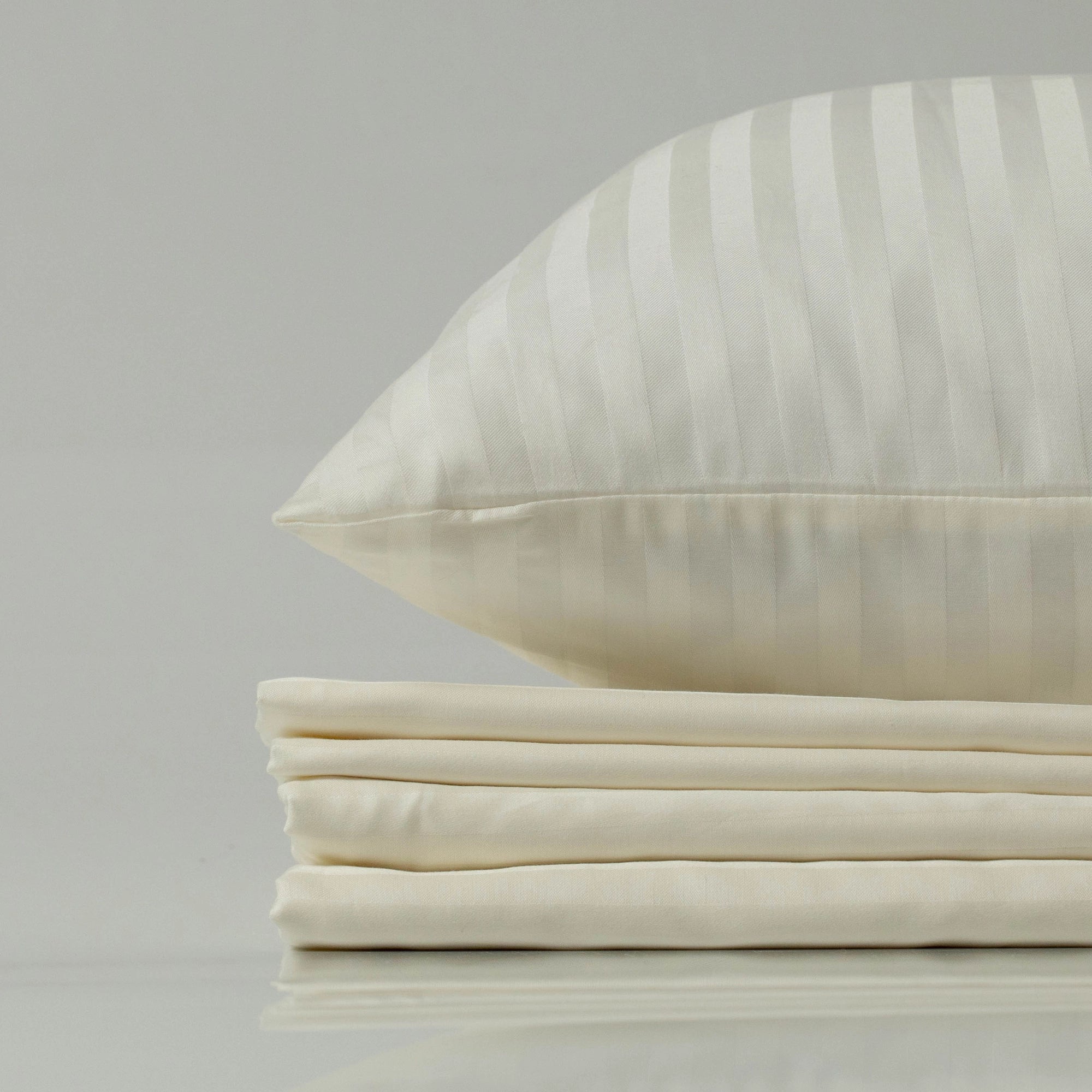 Supreme Rest Ivory Dune striped sateen pillowcase on a neatly stacked bedding set.