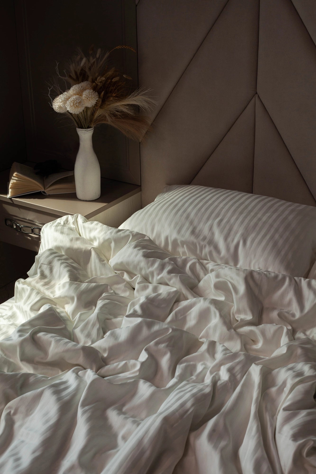 Elegant bedside setup with Ivory Dune bedding, featuring a fluffy duvet and plush pillows.