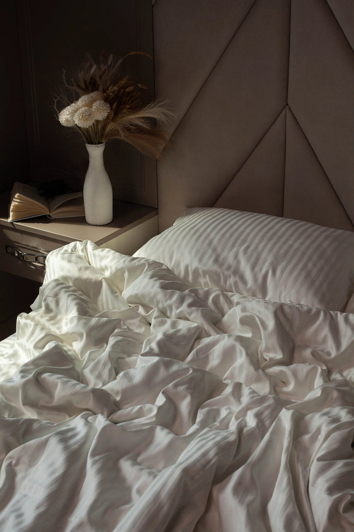 Elegant bedside setup with Ivory Dune bedding, featuring a fluffy duvet and plush pillows.