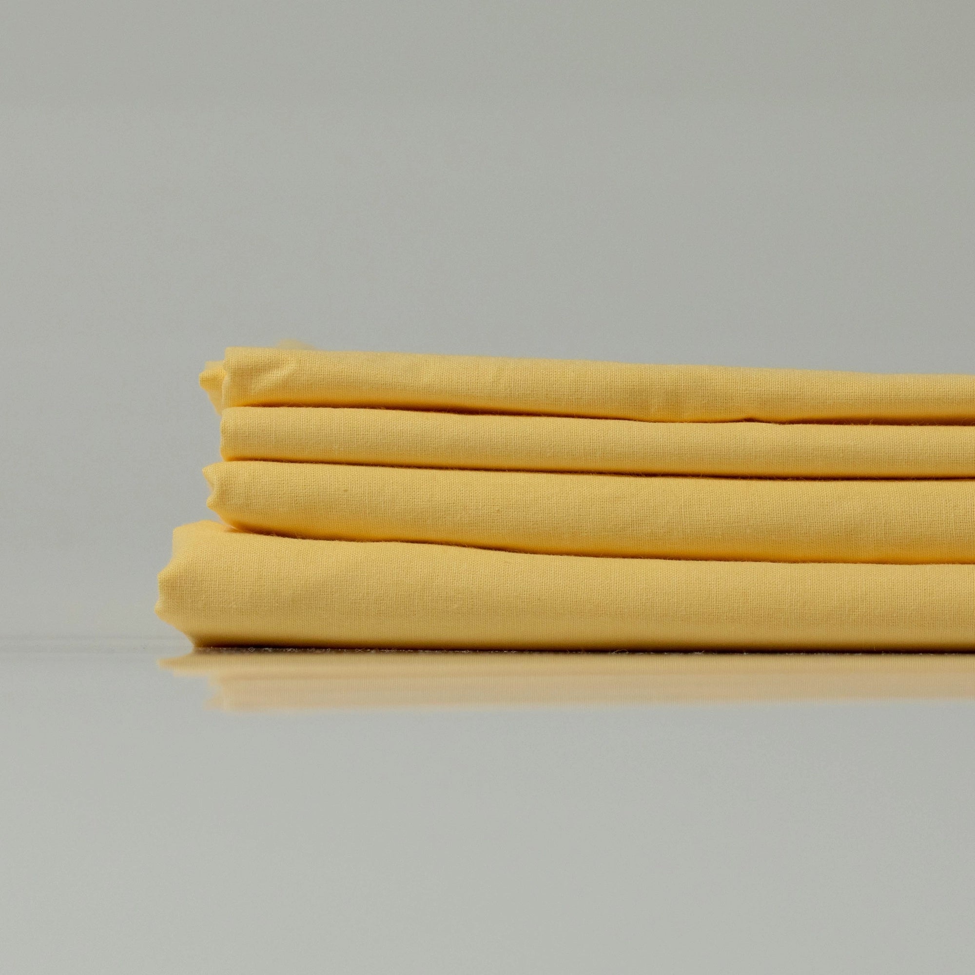 Stack of lemon-yellow ranforce sheets, highlighting their lightweight and breathable texture.