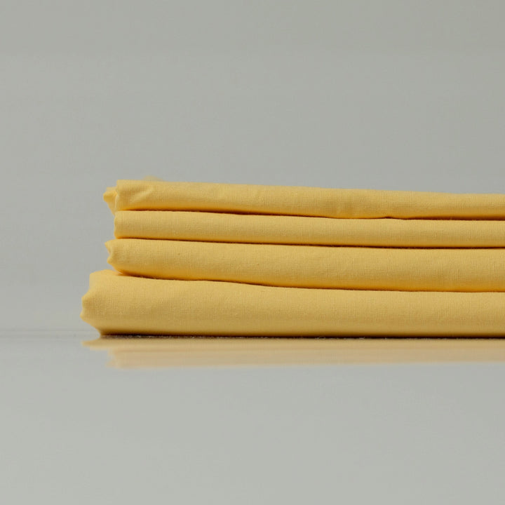 Stack of lemon-yellow ranforce sheets, highlighting their lightweight and breathable texture.
