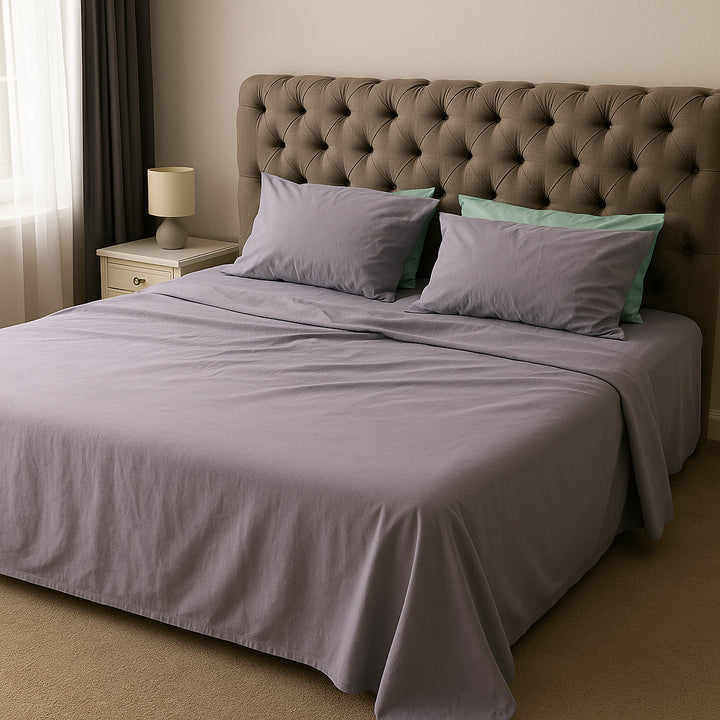 Soft lavender bedding paired with mint green pillows, styled on a refined fabric-paneled bed—an effortlessly serene setup by Supreme Rest, perfect for relaxed mornings.