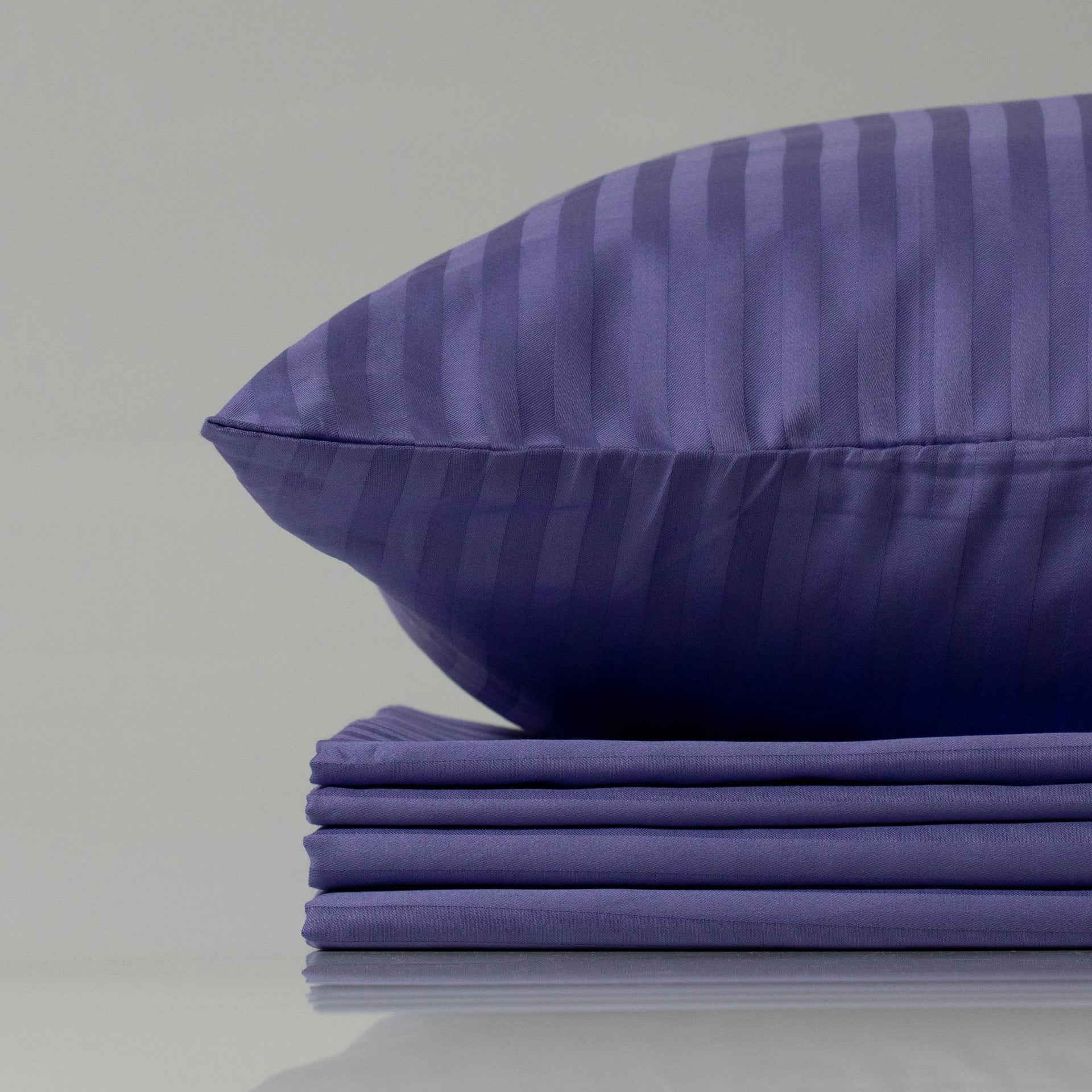 Supreme Rest Patagonian Lupine striped sateen pillowcase resting on a neatly stacked bedding set.