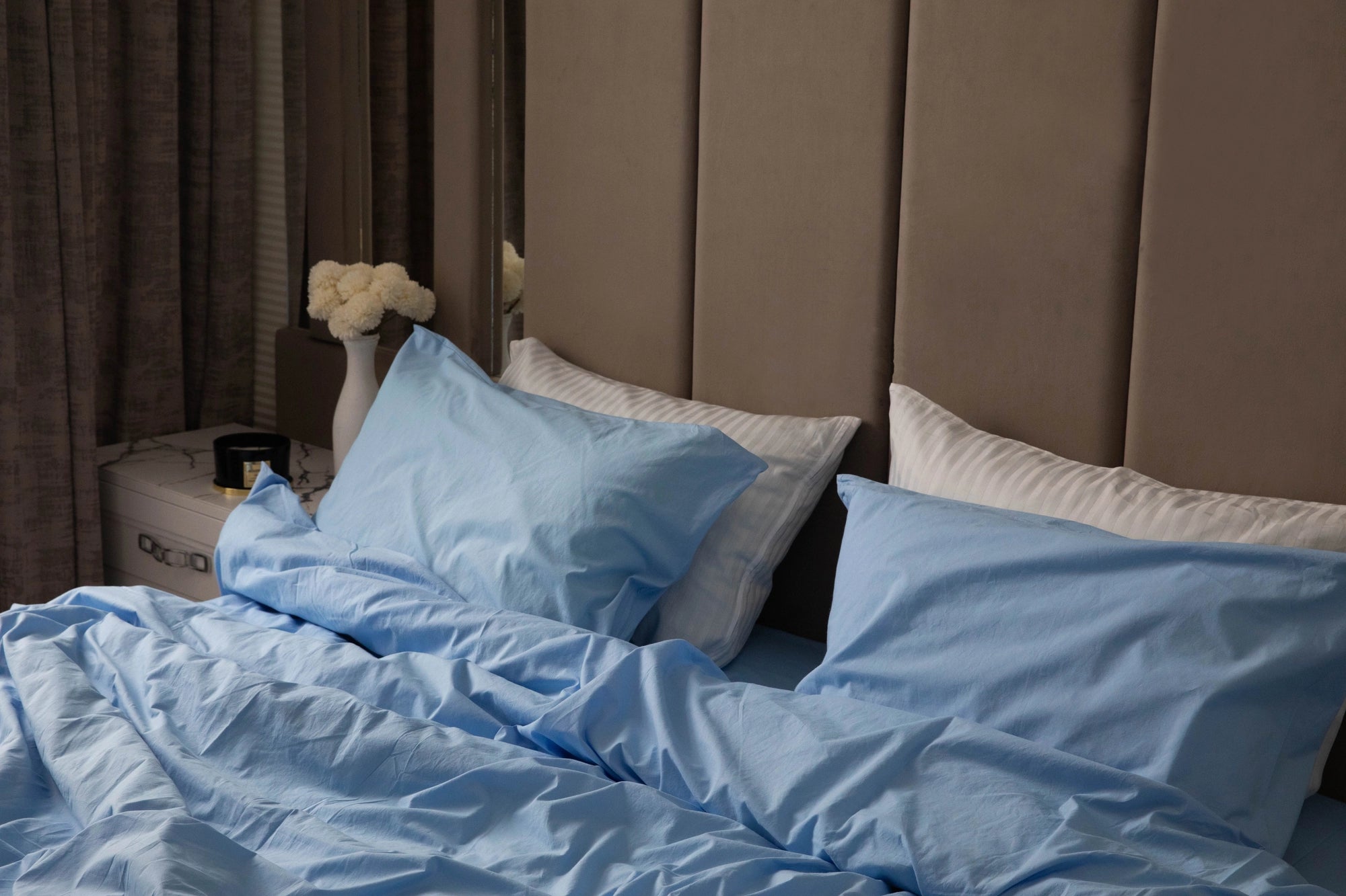 Custom-made, eco-friendly stonewashed cotton bedding by Supreme Rest in soft blue, layered with striped pillows for a crafted, relaxed luxury look