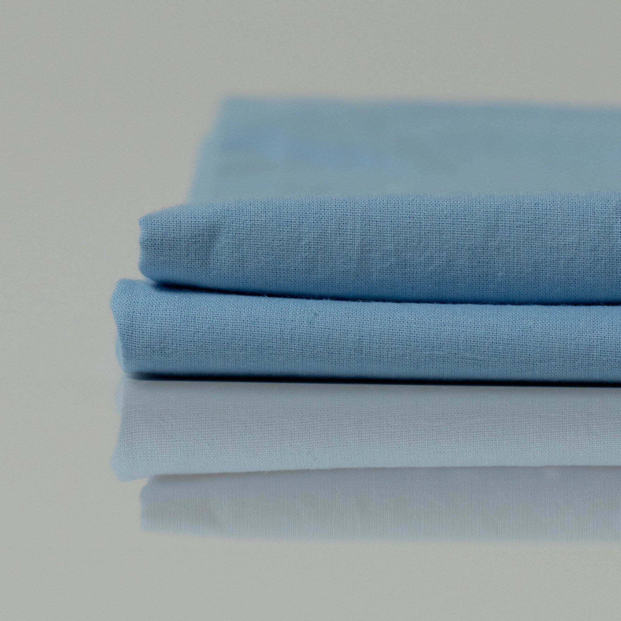 Folded light blue stonewashed cotton bedding, thoughtfully crafted by Supreme Rest using eco-friendly materials for a custom-made, airy finish.