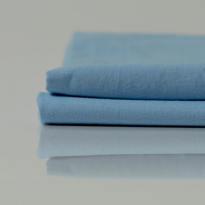 Folded light blue stonewashed cotton bedding, thoughtfully crafted by Supreme Rest using eco-friendly materials for a custom-made, airy finish.