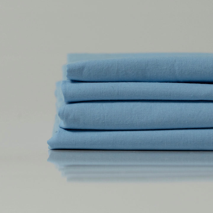Neatly folded stonewashed cotton sheets in soft blue, custom made by Supreme Rest with eco-friendly craftsmanship for a serene, breathable sleep experience
