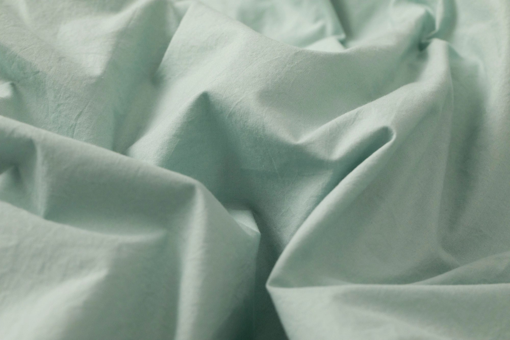 Close-up of Supreme Rest’s eco-friendly fabric in sage green, capturing the gentle drape and fine craft of custom made bedding