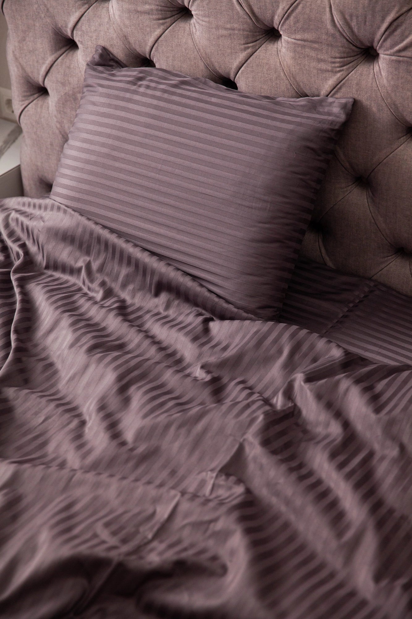 Supreme Rest custom made striped bedding in a deep plum tone, styled on a tufted headboard bed for a luxurious and eco-friendly bedroom aesthetic