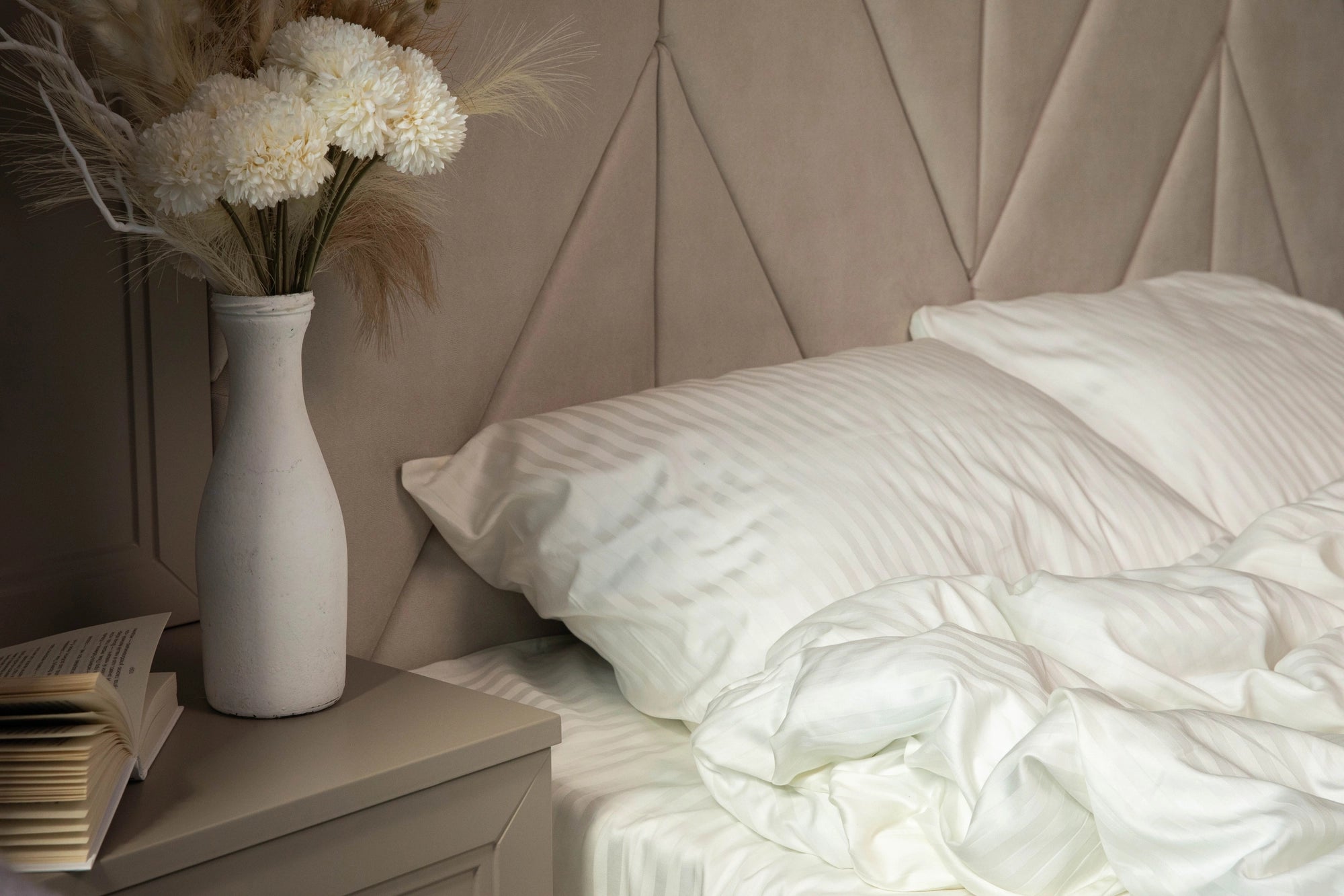 Ivory Dune duvet cover and pillowcases styled on a bed with decorative pillows and warm lighting.