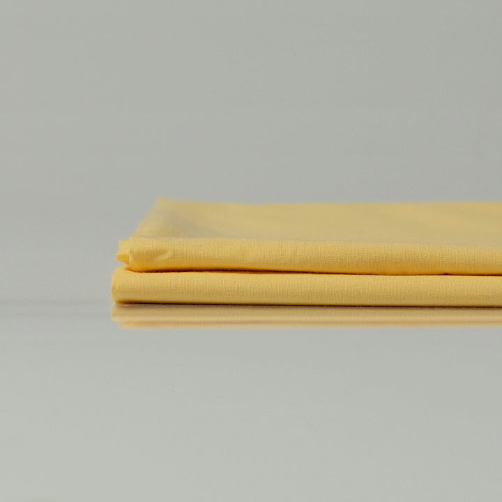 Neatly folded Supreme Rest Lemon Sunbeam ranforce sheets in soft yellow, showcasing smooth texture and breathable cotton fabric.