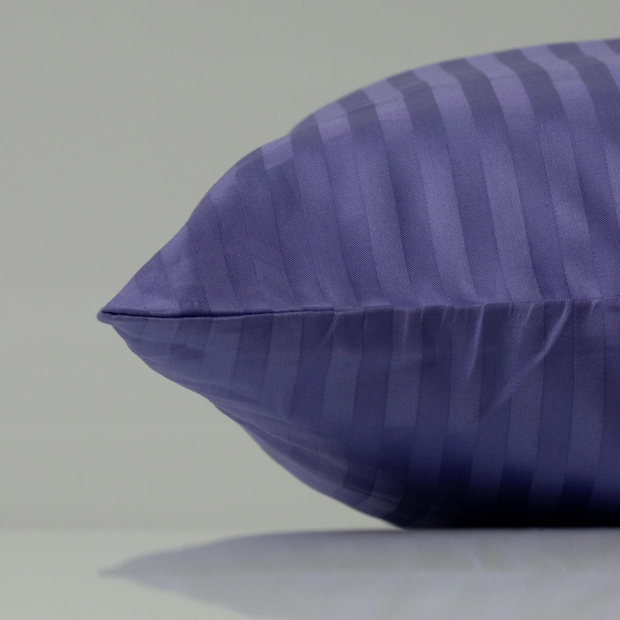 Deep purple pillowcase with a striped sateen finish, adding a touch of sophistication to the bed.
