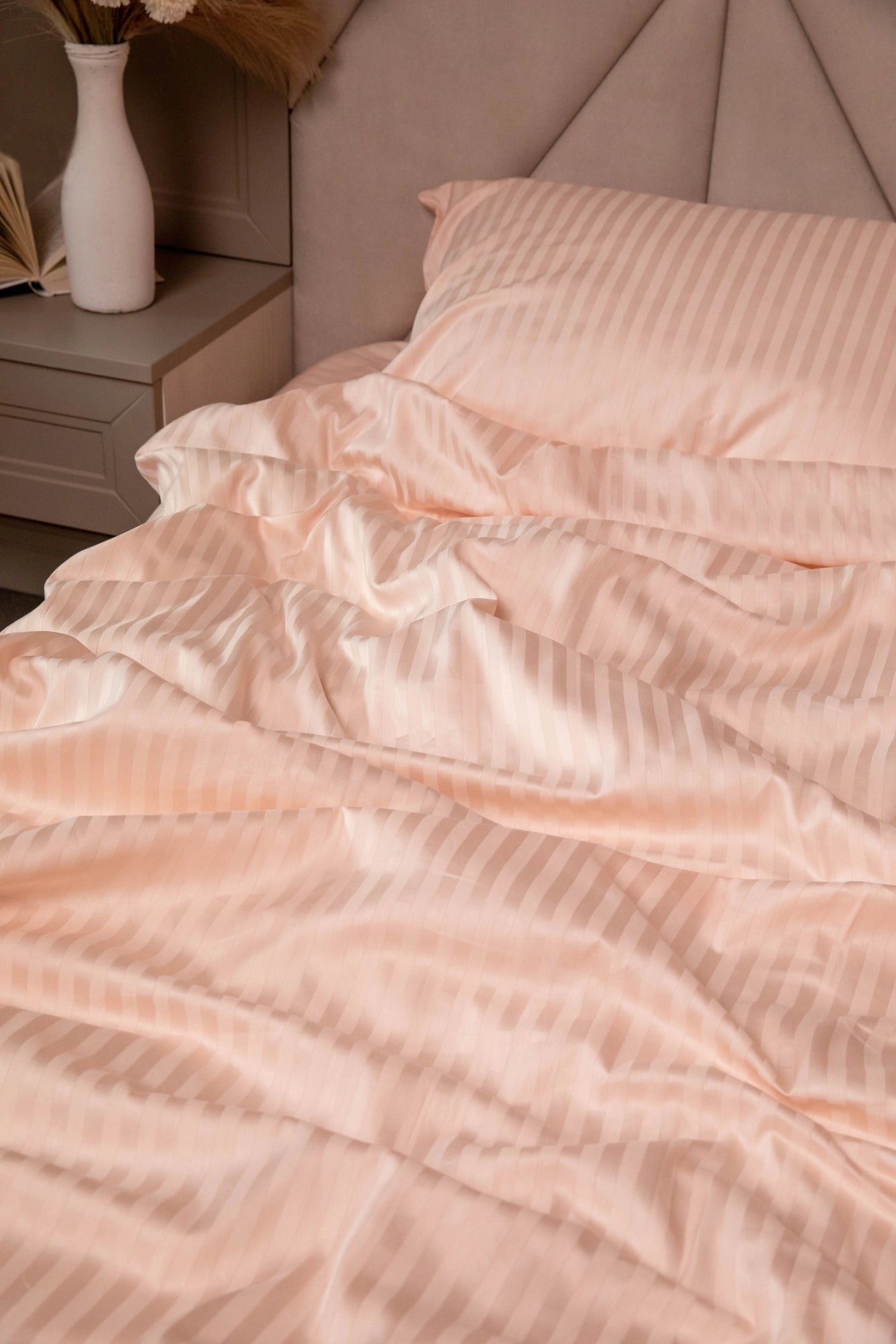 Supreme Rest blush-toned bedding set with subtle satin stripes, styled in a serene bedroom for an inviting, eco-friendly luxury look