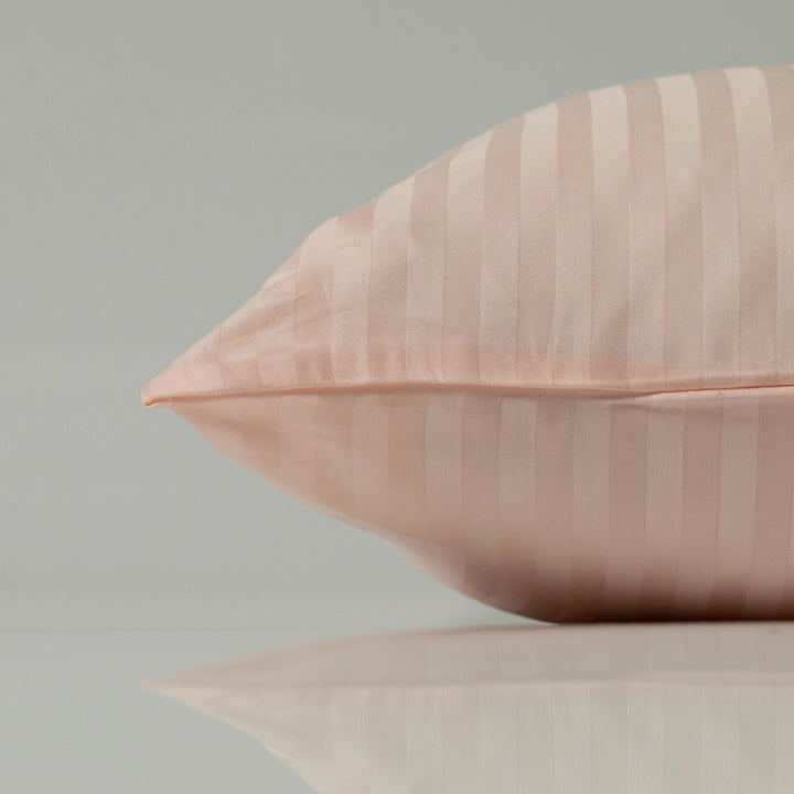 Striped peach pillow resting on a glossy surface with soft reflections and smooth fabric texture