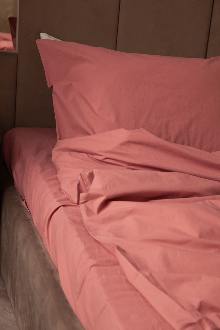 Close-up of a rose-hued pillow and sheet set from Supreme Rest, highlighting the custom made quality and eco-friendly comfort of the bedding
