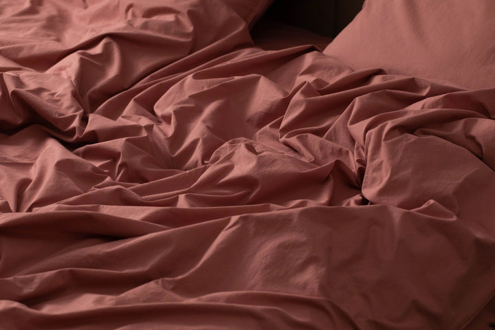 A soft tangle of rose-colored sheets from Supreme Rest, showcasing the brand’s eco-friendly craftsmanship and luxurious custom made bedding