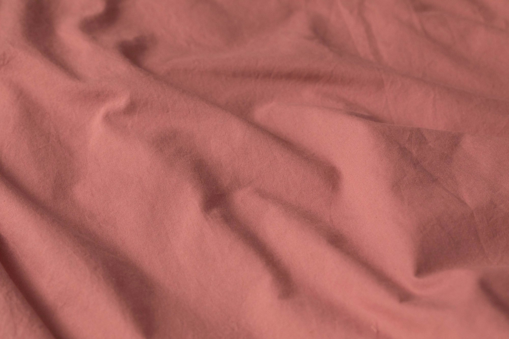 Detail shot of Supreme Rest’s stonewashed cotton in a warm rose tone, highlighting its naturally relaxed texture and eco-friendly craftsmanship.
