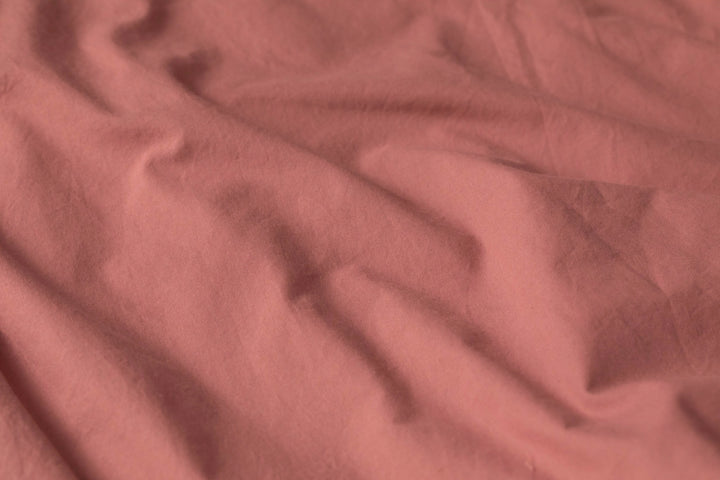 Detail shot of Supreme Rest’s stonewashed cotton in a warm rose tone, highlighting its naturally relaxed texture and eco-friendly craftsmanship.