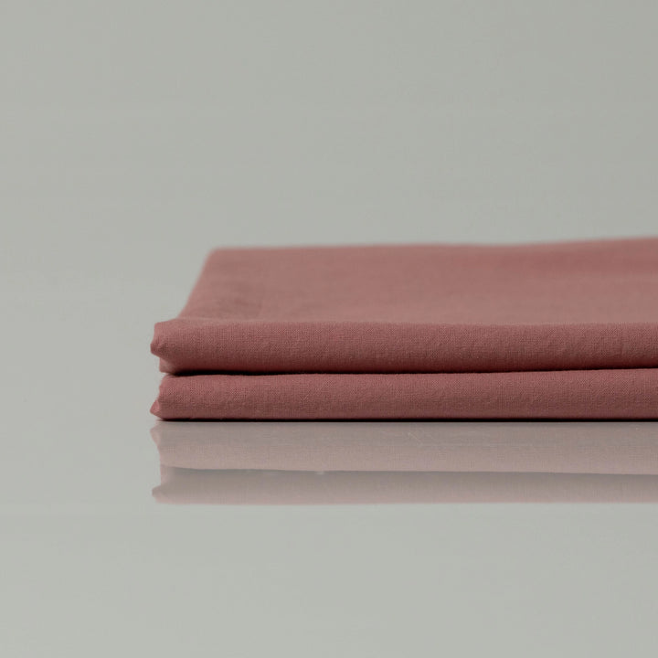 Folded terracotta-toned cotton sheet resting neatly, radiating calm with its matte weave and earthy sophistication.