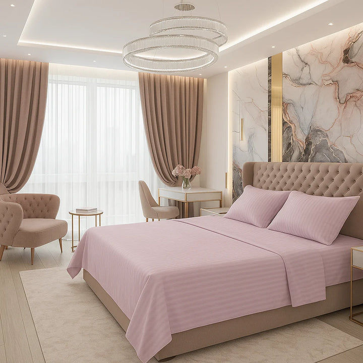Soft pink striped bedding with matching pillows on a tufted beige bed frame, styled with marble wall art, elegant chandeliers, and taupe curtains in a modern sunlit bedroom