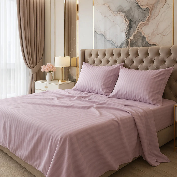Lavender striped bed sheets with matching pillows on a tufted headboard bed, styled with gold-accent bedside tables, warm lighting, and marble wall art in a softly lit bedroom