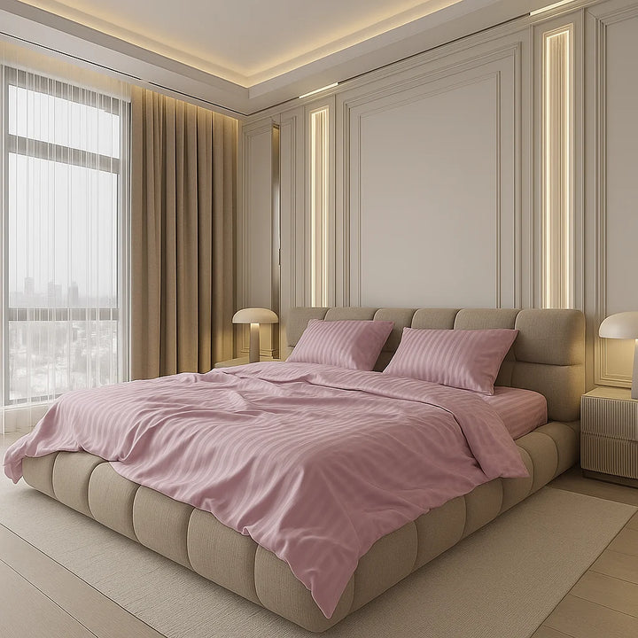 Soft mauve bedding with subtle stripes styled in a modern bedroom featuring a tufted beige bed frame, fluted wall panels, warm lighting accents, and floor-to-ceiling curtains beside a large window