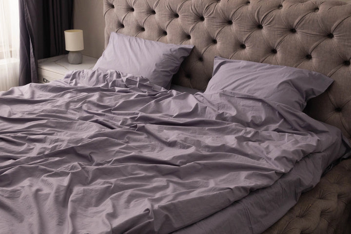 A soft cotton branch rests atop folded white linens from Supreme Rest - a serene symbol of our devotion to eco-friendly comfort, where every fabric is a quiet promise of nature, purity, and craft