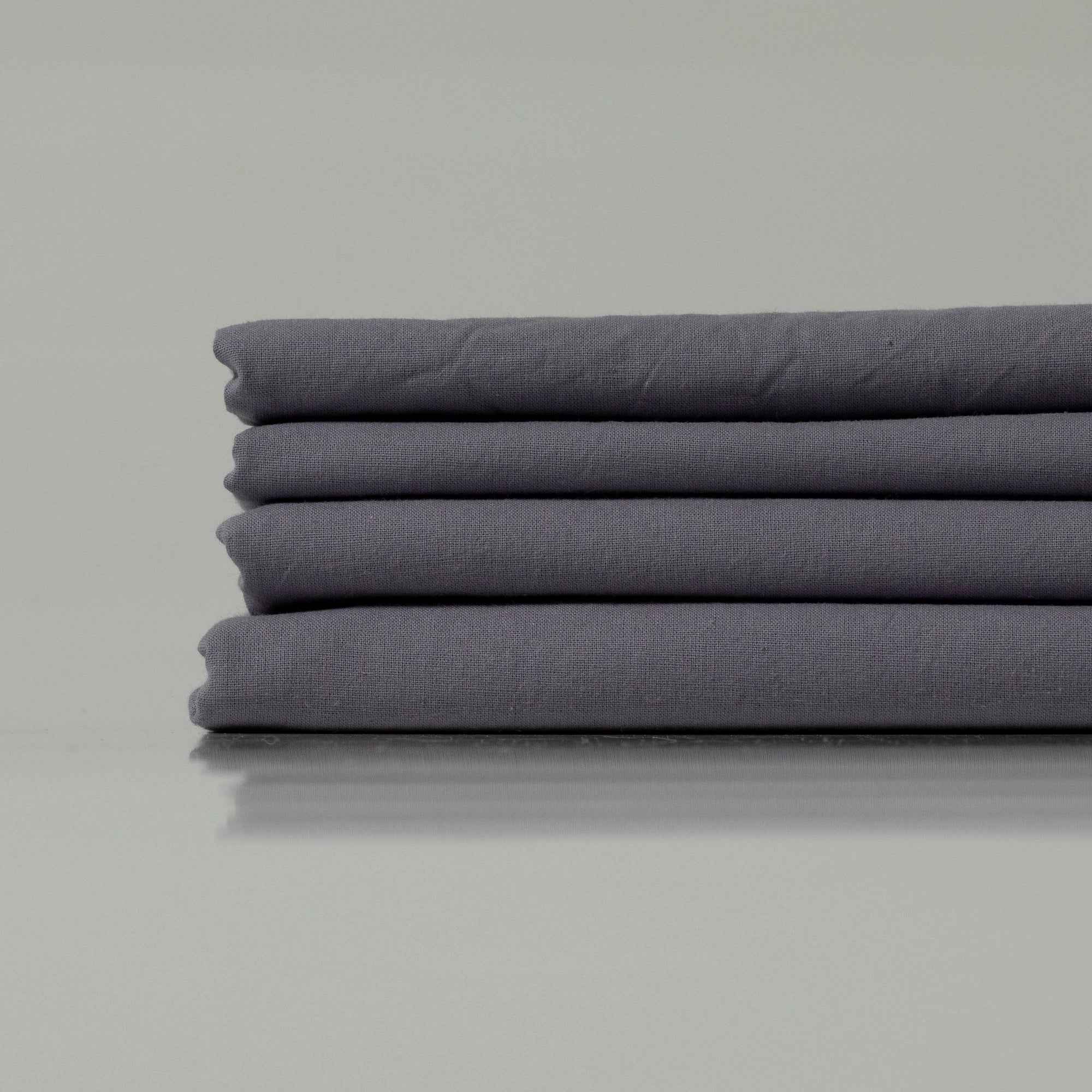 Neatly stacked bedding in a cool charcoal hue, showcasing refined craftsmanship and a soft, matte finish
