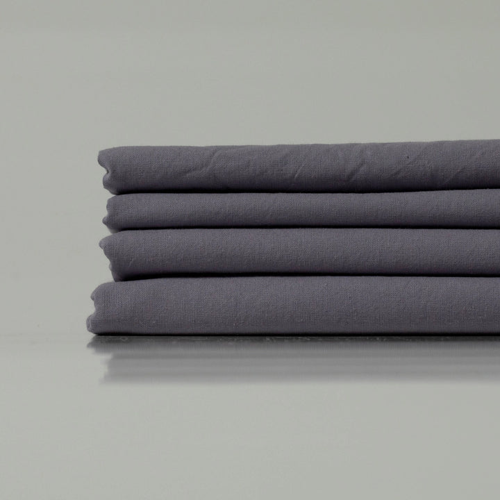 Neatly stacked bedding in a cool charcoal hue, showcasing refined craftsmanship and a soft, matte finish