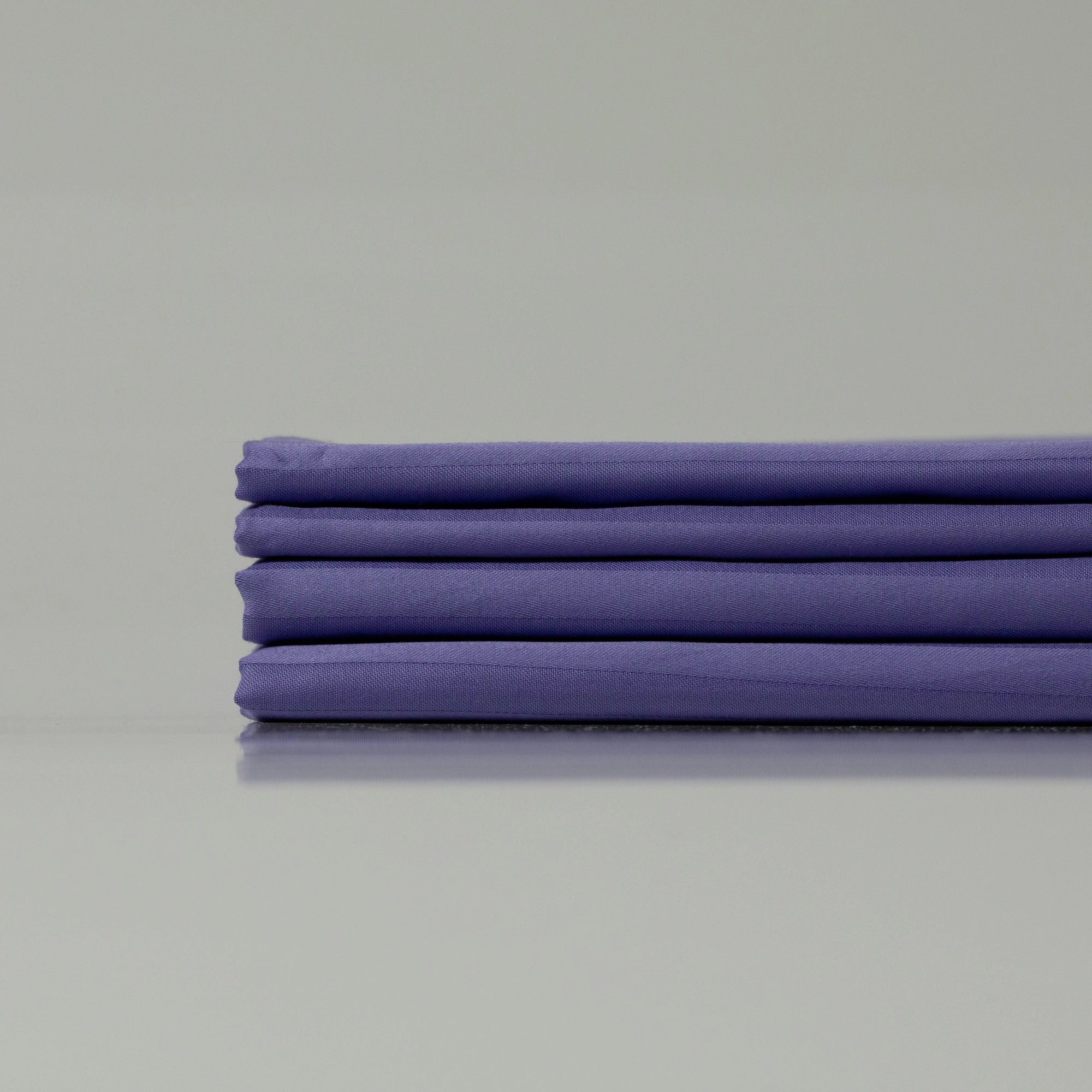 Neatly arranged deep purple sateen bedding set, emphasizing breathable and silky smooth fabric.