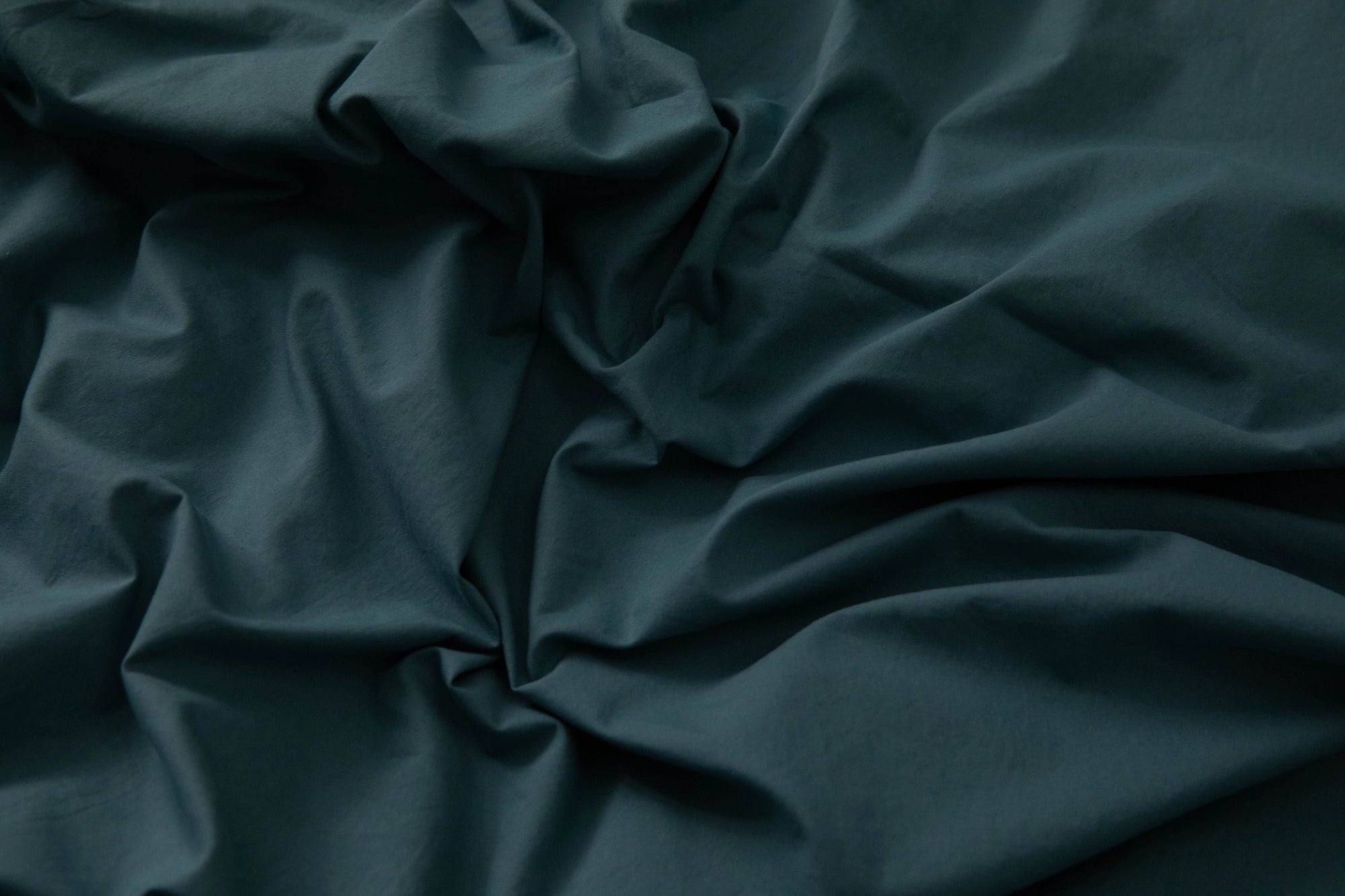 Supreme Rest teal Stonewashed Cotton sheet gently rumpled across the bed, showcasing its relaxed, lived-in softness and effortless elegance