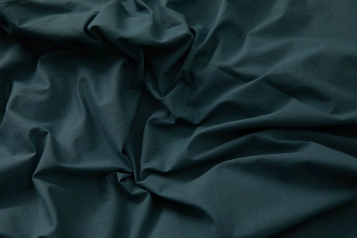 Supreme Rest teal Stonewashed Cotton sheet gently rumpled across the bed, showcasing its relaxed, lived-in softness and effortless elegance