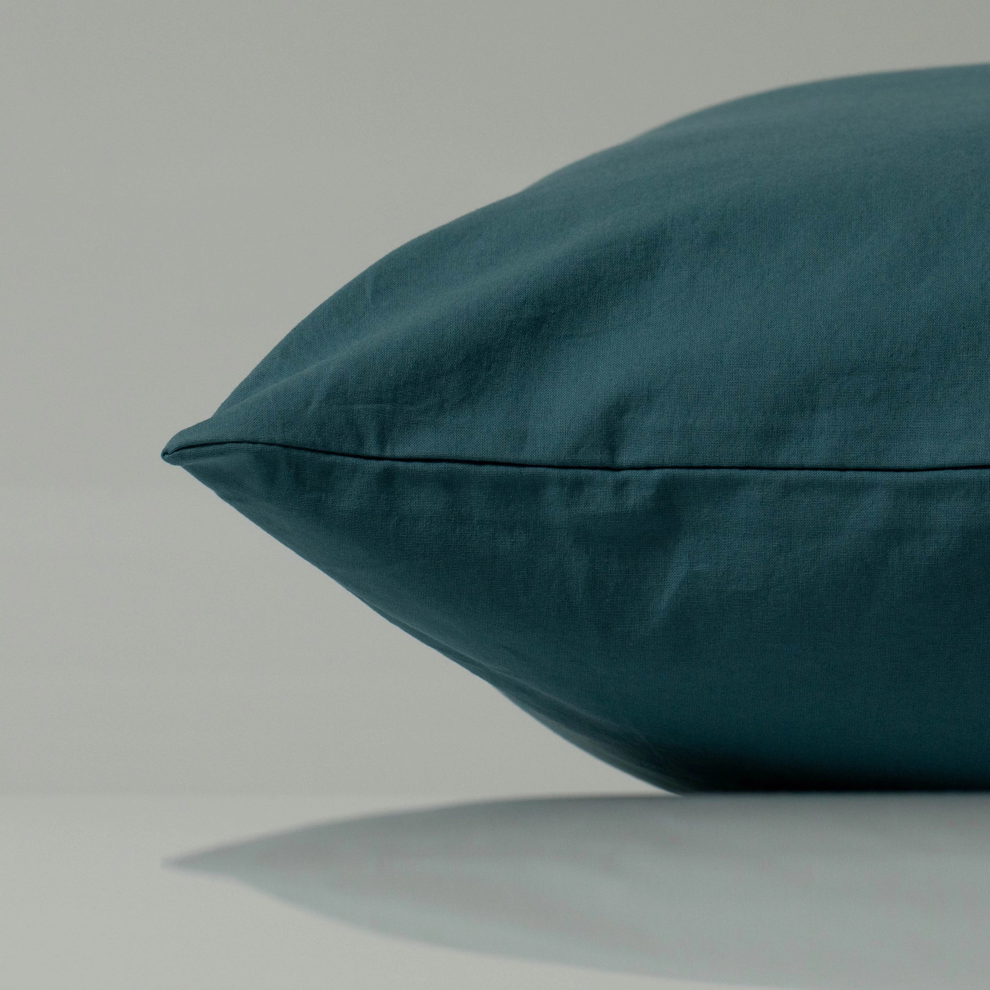 Deep cyan pillow with a minimalist silhouette, showcasing its handcrafted finish and smooth, natural texture