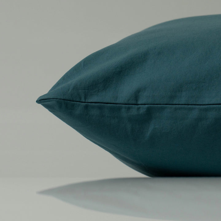Deep cyan pillow with a minimalist silhouette, showcasing its handcrafted finish and smooth, natural texture