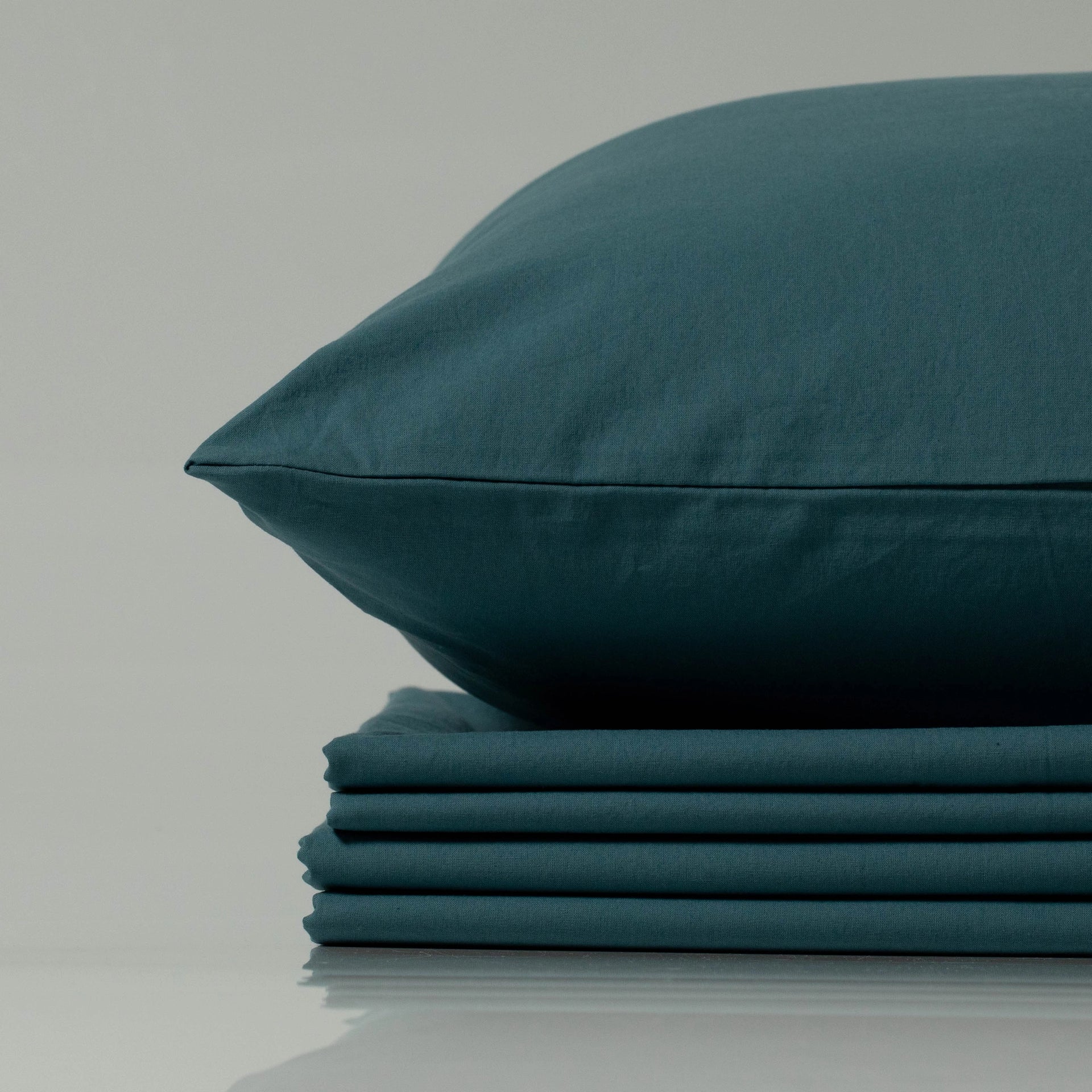 Supreme Rest deep teal bedding set, eco-friendly and custom made, featuring a neatly stacked sheet bundle topped with a perfectly tailored pillow
