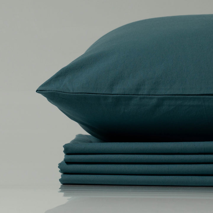 Supreme Rest deep teal bedding set, eco-friendly and custom made, featuring a neatly stacked sheet bundle topped with a perfectly tailored pillow