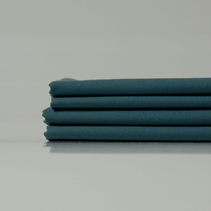 Stacked deep teal bed sheets from Supreme Rest, crafted with precision and eco-friendly materials for a luxurious, custom bedding experience