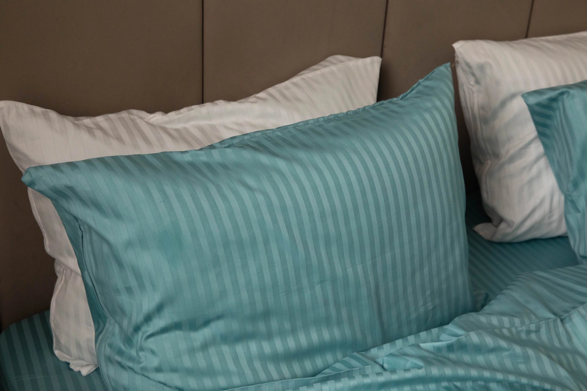 Supreme Rest teal striped bedding and pillows arranged on a bed, highlighting custom made, eco-friendly luxury