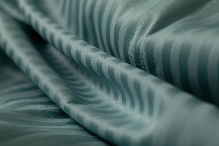 Luxurious teal striped fabric with a smooth, flowing drape, highlighting refined craftsmanship and premium texture