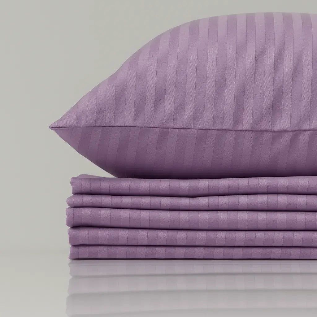 Purple striped pillow and bed sheets on a light gray background
