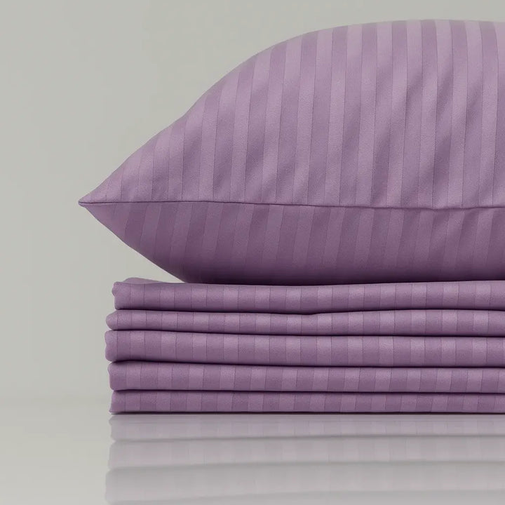 Purple striped pillow and bed sheets on a light gray background