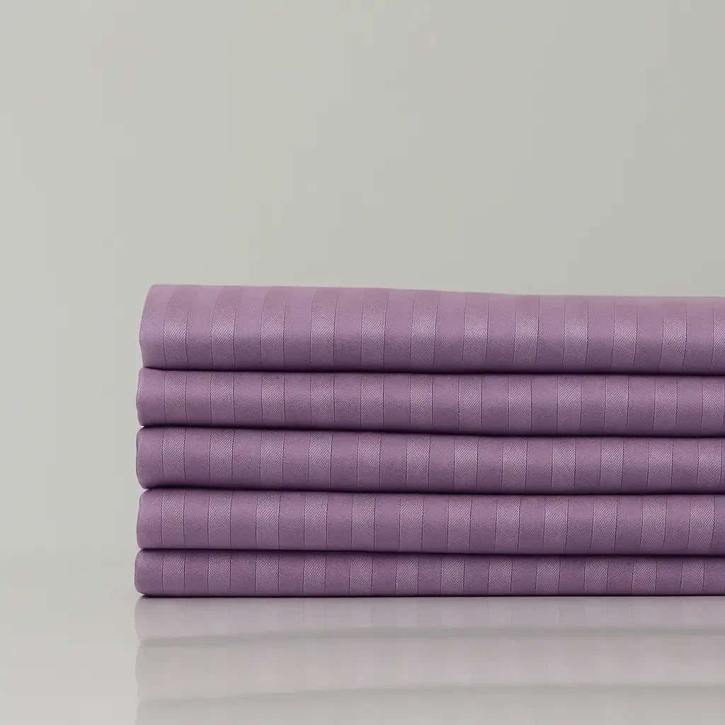 Premium “Wisteria Whisper” lilac sateen sheets, folded neatly, offering hotel-style comfort and timeless bedroom style.